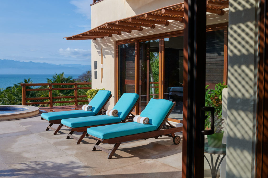 Poolside loungers at The St. Regis Punta Mita Resort, with palm trees and ocean views.